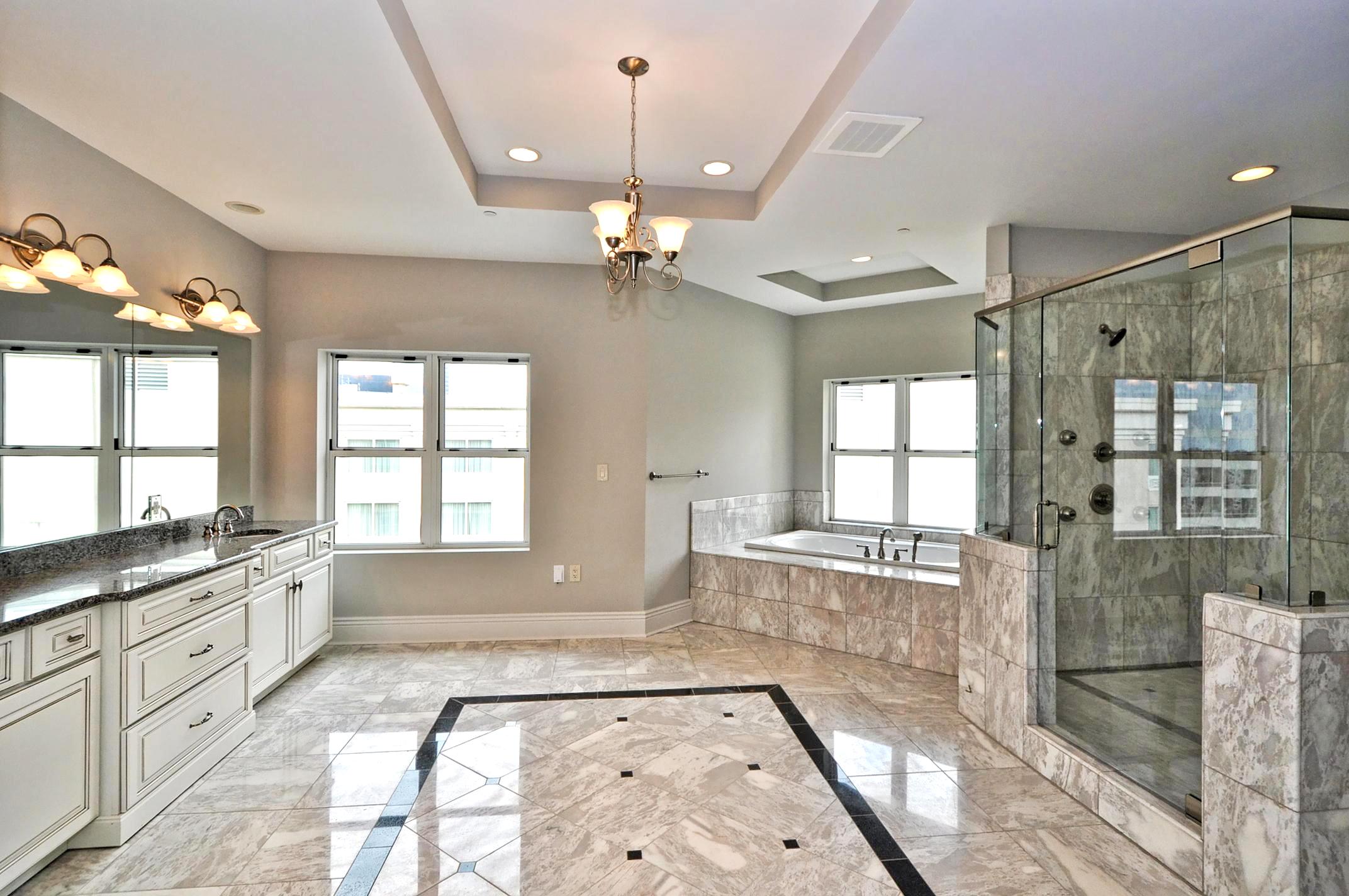 Finished bathroom with marble-look tile, dual vanity, and a glass walk-in shower